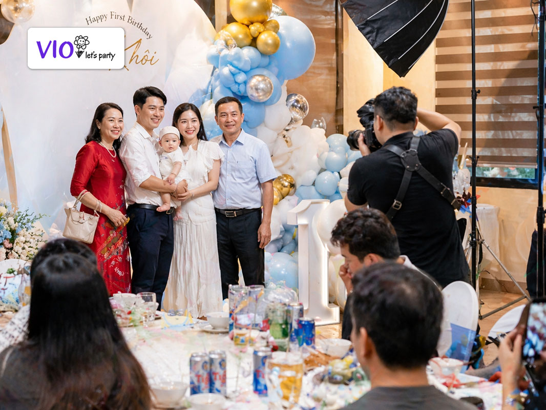 Nhiếp ảnh gia VioParty đang chụp ảnh cho bé và gia đình trong tiệc thôi nôi của bé