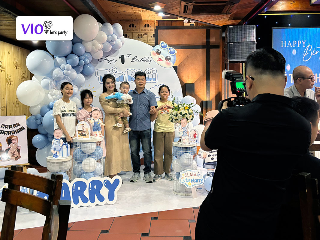 nhiếp ảnh gia VioParty đang chụp gia đình chủ tiệc sinh nhật, thôi nôi với khách mời cạnh background bằng bong bóng lung linh