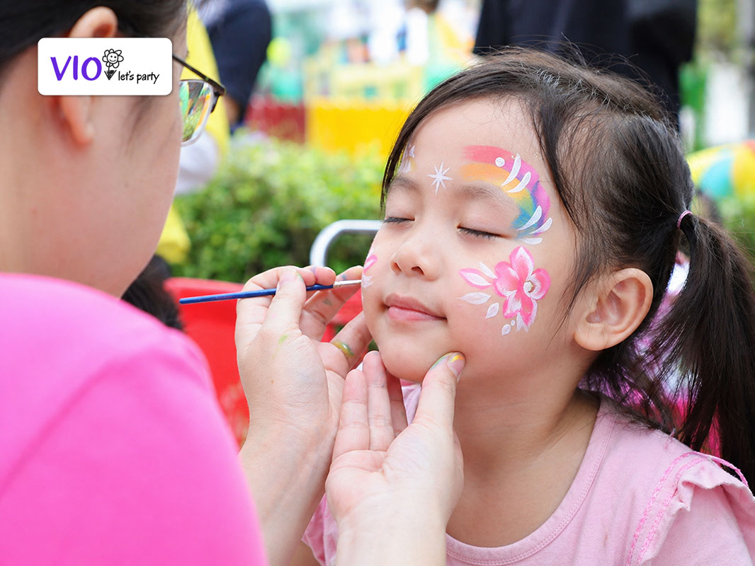 Họa sĩ Face Painting đang vẽ mặt cho bé tại tiệc sinh nhật